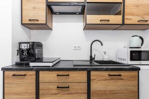 A compact kitchen area featuring wooden cabinets, a microwave, stove, and coffee maker. Functional and modern, with ample storage.