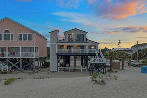 As the day fades, find solace in this stilted beach home that offers stunning sunset views from its welcoming porches, promising a haven of relaxation with the rhythmic sounds of the ocean wav