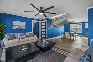 Step inside this modern living space that artfully combines comfort and style, featuring sleek furnishings, cool tones, and a splash of coastal essence.