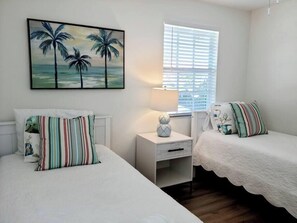 Twin bedroom with tropical decor, ceiling fan & closet.