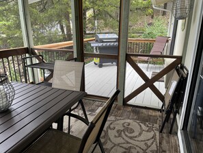 Screened in deck connects to deck with gas grill.