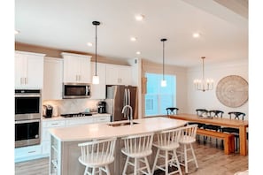 Open design includes large kitchen island with 4 stools, kitchen table seats 10.