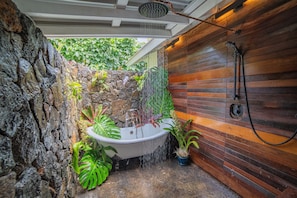 Custom private outdoor shower with 3 shower heads, double tub, rock wall orchids