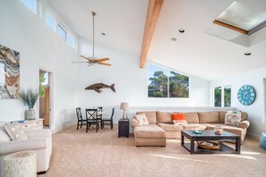 Lofted lounge area features a large sectional, a game table, tons of natural light, and an ocean view.