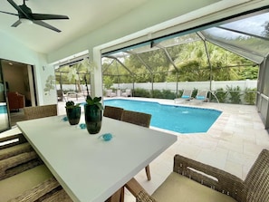 Covered& screened poolside outdoor dining area with seating for up to six guests
