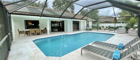 Newly remodeled heated pool w/ screened lanai, lounging areas, and dining table