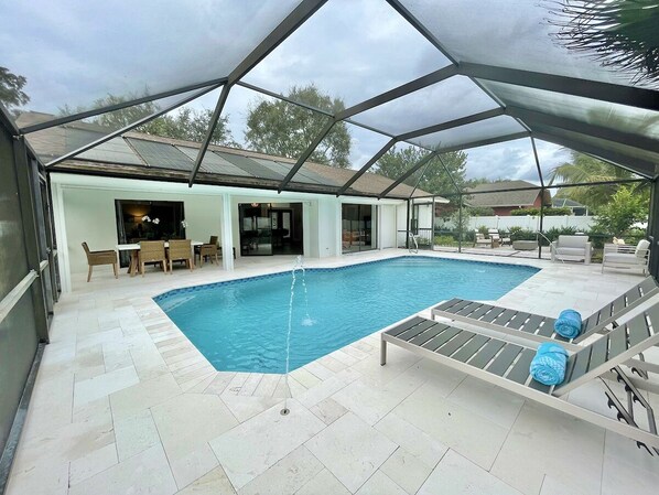 Newly remodeled heated pool w/ screened lanai, lounging areas, and dining table