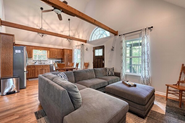Spacious living room with vaulted ceilings, rustic beams, and an open kitchen