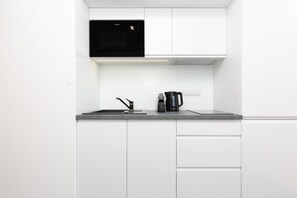 A sleek white kitchen with clean lines, modern cabinetry, and essential appliances.
