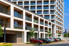 The exterior of a modern apartment building with a contemporary facade and neatly landscaped surroundings.
