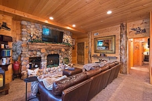 The living area, complete with a stunning river rock fireplace, large leather sectional, flat-screen TV and views of your private patio and hot tub space, places you in the center of the fun in this rustic, open space.