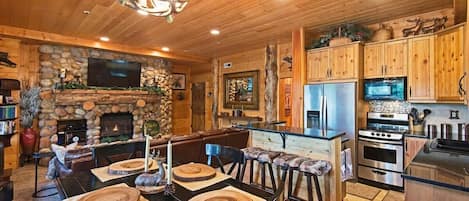 Classic cabin ambiance abounds in the open-concept kitchen/living/dining room area with its river rock fireplace and wood beam details. The kitchen boasts stainless steel appliances and a roomy island with bar seating.
