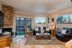 Living Room with 65" Sony Smart TV, wood-burning fireplace, plush leather furnishings, and private balcony access overlooking Park Ave.