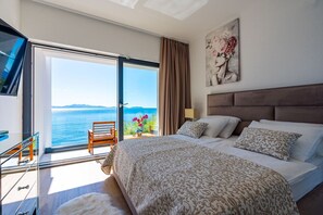Luxury air-conditioned bedroom with king size bed, LCD TV and balcony in seafront modern rental villa Blue Planet

