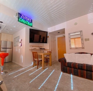 View of the front door entrance, intimate dining area, love seat sofa, and flat-screen TV