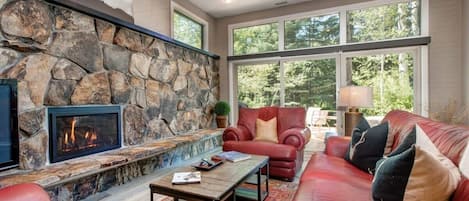 Framed by picture windows with views of Hidden Creek and anchored by a striking stone fireplace, this living room invites you in with plush, leather furnishings, a large flat-screen TV and a coffee table for peak relaxation.