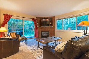 Family room with a luxurious leather sofa, armchair seating, indoor gas fireplace, and a flat-screen TV