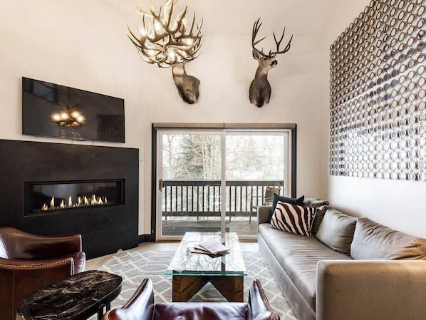With striking, modern mountain decor, sleek finishes, a stunning fireplace, large flat-screen TV and cozy seating options, this inviting living room makes for an ideal place to relax after a day on the slopes.
