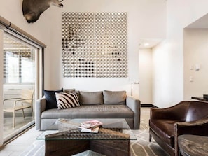The comfortable living room sofa is highlighted by dramatic wall art and a glimpse of the lovely outdoor patio space