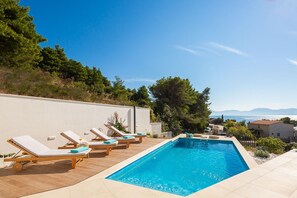 Outdoor pool with deck chairs in Makarska Croatian luxury villa for vacation and rent with total privacy.