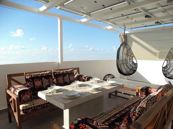 Your private rooftop features sunshades, & luxe Aztec pillows on rustic benches.