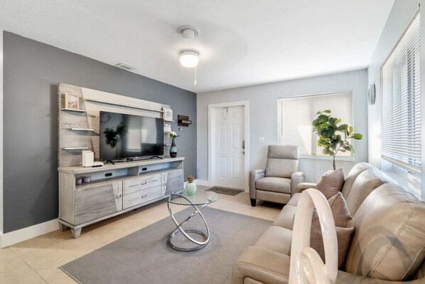 This living room is all about the natural light. The large windows let in plenty of sunshine, making the space feel bright and airy. The plants add a touch of life and freshness.