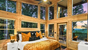 This spacious king bedroom features oversized windows that fill the space with natural light and breathtaking views of the outdoors.