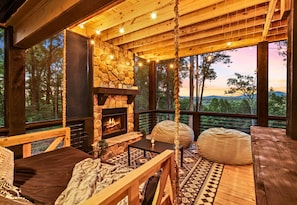 The covered deck features a cozy fireplace and plush seating, making it a perfect spot to relax and enjoy the mountain air in any weather.