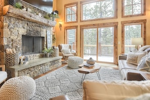 Main floor living room with beautiful wood burning fireplace and large windows to take in all of the gorgeous views