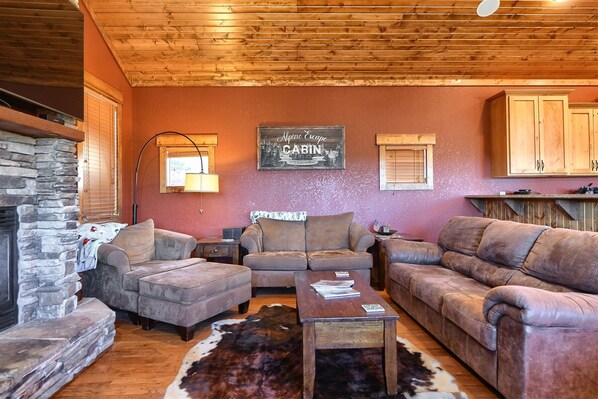 Main floor living room with plenty of seating, a large flat screen TV, and gas fireplace