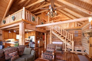 Bask in the warmth of this spacious log cabin’s main living area, featuring an open floor plan, cozy electric fireplace, and Smart TV.