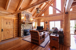 Bask in the warmth of this spacious log cabin’s main living area, featuring an open floor plan, cozy electric fireplace, and Smart TV.
