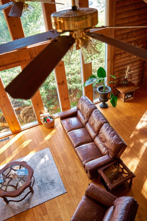 Cozy Spacious Living room showcases exposed log beams with Panoramic Windows