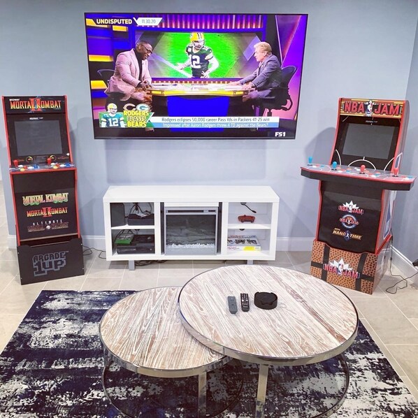 Living room, with arcade, Roku Tv, electric fire place, and game consoles.