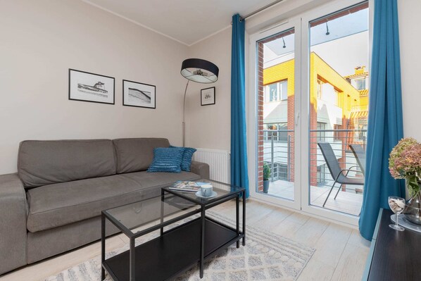 Bright and cozy living room with a comfortable gray sofa, sleek coffee table, and soft lighting. Ideal for relaxing or hosting guests in a modern environment.