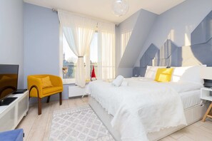 Charming bedroom with a sloped ceiling, soft bedding, and warm lighting. A unique retreat combining comfort and character.