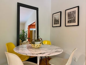 The breakfast nook, off the kitchen, features a buttery leather couch and this marble dining table with seating for 4. Playful Eames chairs pick up and continue a fun theme of yellow highlights throughout the house. Walls: San Francisco photography.