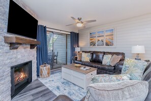 Living room - This gorgeous room features a pullout sofa, stunning stone laid faux fireplace and access to the back deck.