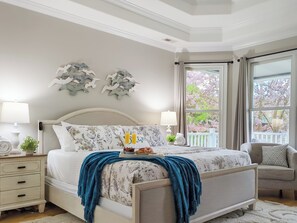 Primary suite with King bed, cell phone inductive chargers, suitcase stand, TV and water views.