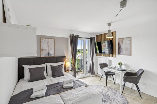 Cozy studio apartment with box spring bed, dining and work table, smart TV and balcony
