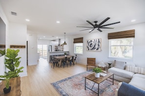 The living room flows into the dining, bar, kitchen, and outdoor patio.