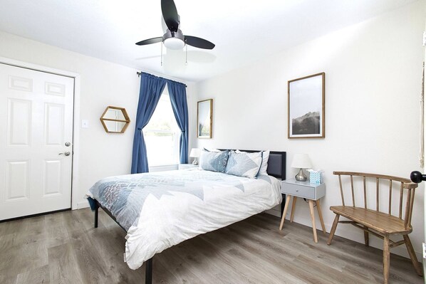 The primary bedroom features a comfortable queen sized bed with two side tables and reading lamps. This bedroom also has a generous walk in closet and dresser