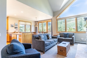 Living area with new furnishings, Smart TV, vaulted ceilings, and a gas fireplace with beautiful stone surround.