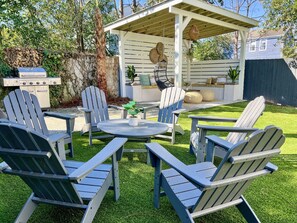 Professionally turfed backyard with ample seating, grill, and custom pergola