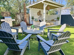 Professionally turfed backyard with ample seating, grill, and custom pergola