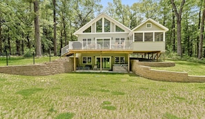 Back of home with upper deck, screened porch, back yard, and patio with hot tub