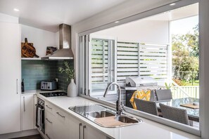The kitchen comes fully equipped for meals at home and has a servery straight to the outdoor dining area.