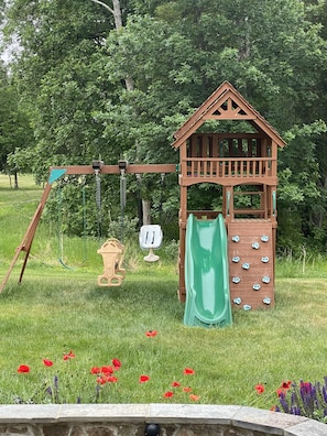 Playground - swings, slide, climbing wall. Sandbox and playhouse not pictured