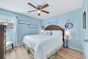 Serene Primary bedroom with king-sized bed. Light blue hues and soft textures create a calming atmosphere.