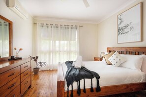 The master bedroom features a plush queen bed, with a ceiling fan and AC.